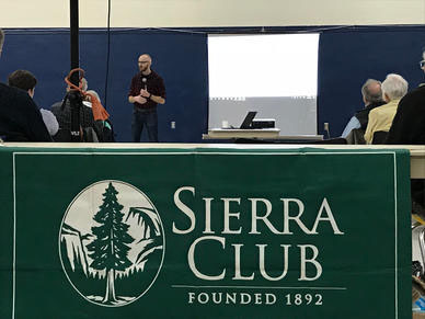 Sierra club logo on a banner with Jeff Bishop speaking behind it.