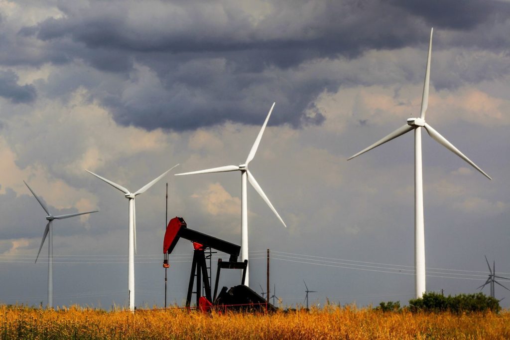 A pumpjack in front of wind turbines in West Texas. Photographer: Orjan F. Ellingvag/Corbis News